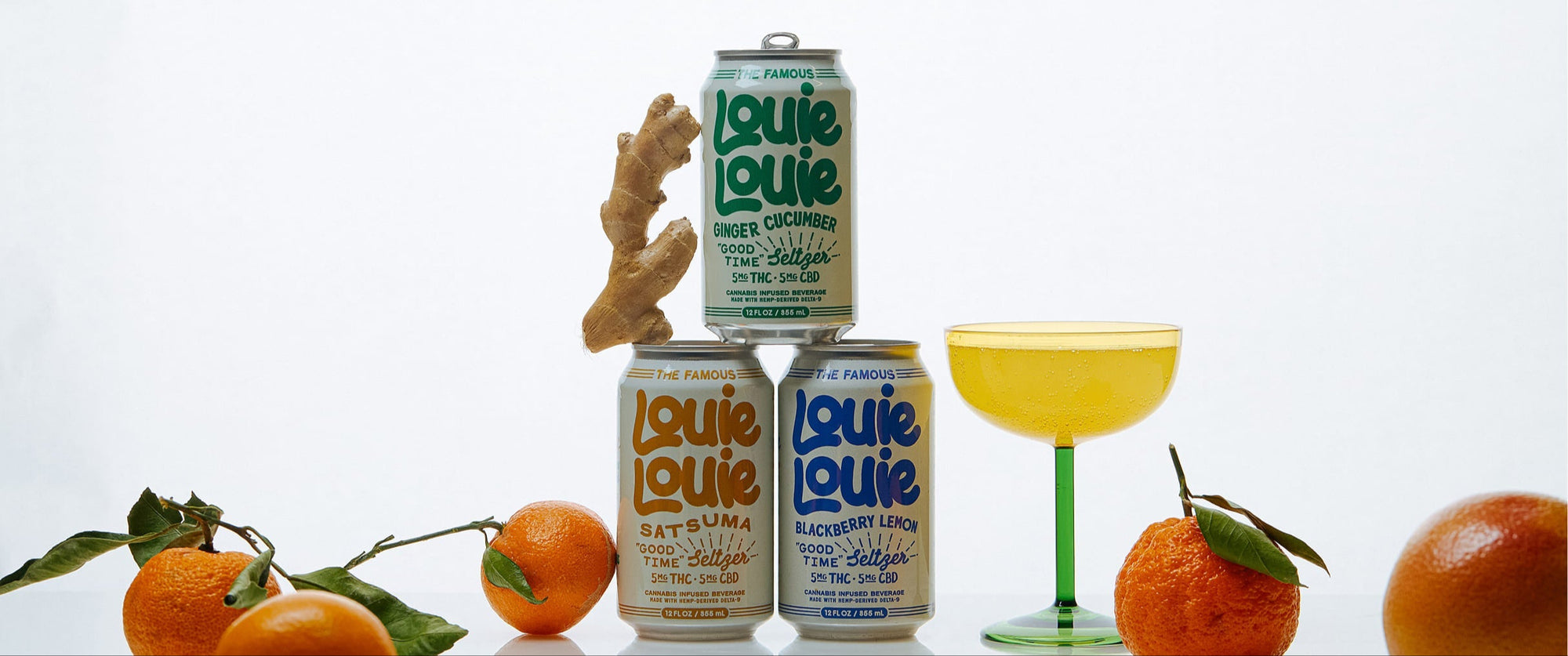 Louie Louie beer cans with oranges and a cocktail on a reflective surface